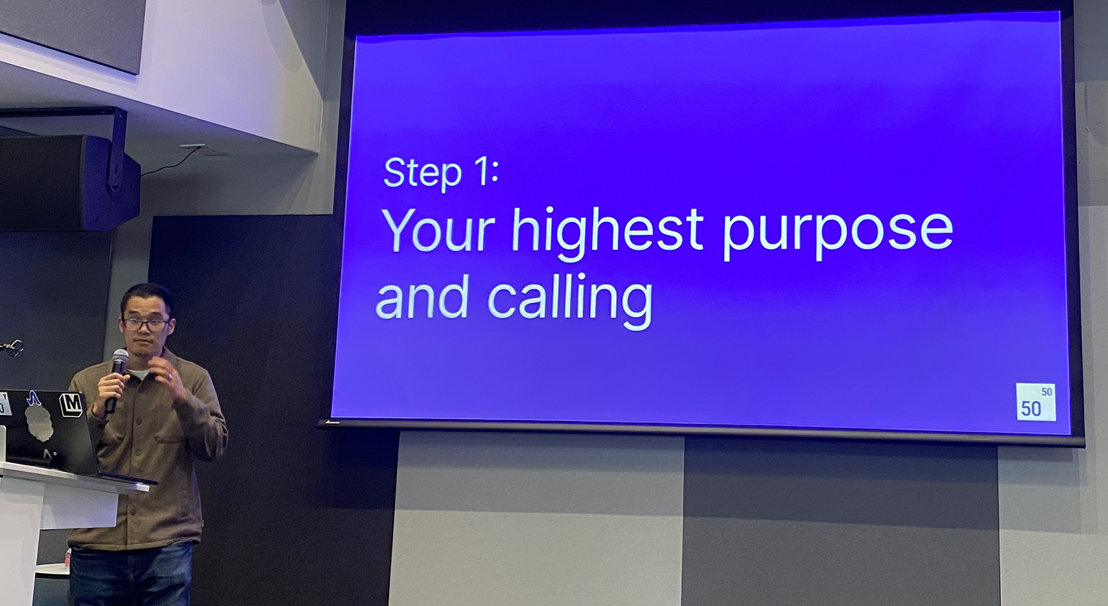 Alex Teng of Fifty Years speaking at UC Berkeley's Bakar Labs, beside a slide reading “Step 1: Your highest purpose and calling.”